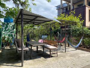 a picnic table and chairs under a canopy with a hammock at Vato tkhilaishvili in Kobuleti