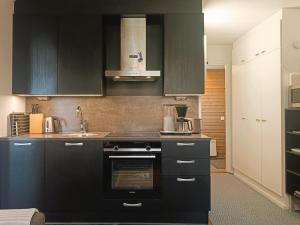 a kitchen with black cabinets and a stove at Revontuli 6 in Syöte +8 photos