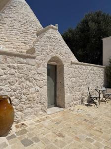 a stone building with a door and a table and chairs at Trullo botanico in Ceglie Messapica