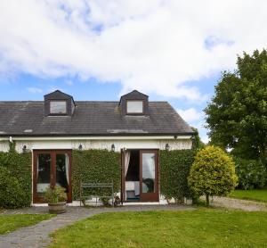 a white house with a green hedge at 2 Bedroom Apartment - Free Parking & Garden in Kilmessan