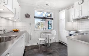 a kitchen with white cabinets and a table and chairs at 2 Bedroom Pet Friendly Home In Ringkøbing in Ringkøbing