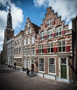 um grande edifício de tijolos com uma torre de relógio numa rua em Boutique Hotel Steenhof Suites - Adults Only em Leiden