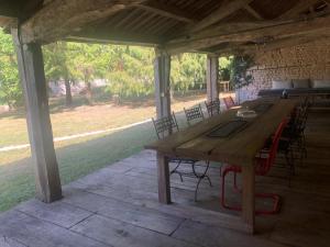 a wooden table and chairs under a pavilion at chambre AZZURO avec jacuzzi lit rond et jardin avec piscine in Saint-Martial-sur-Né