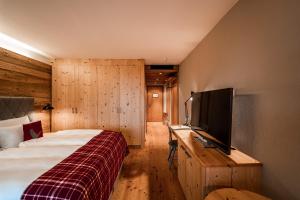 a bedroom with a bed and a flat screen tv at Resort Das Achental in Grassau