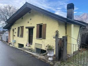 an old yellow house on the side of a street at Casa Helvezia in Cadenazzo