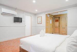 a white bedroom with a bed and a flat screen tv at XXCASA Sukhumvit 39 คาซ่า สุขุมวิท 39 BTS ทองหล่อ in Klong Toi