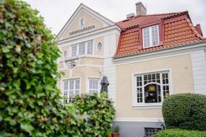 a tan and white building with a red roof at Hotell Dannegården in Trelleborg