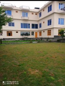 a large white building with a green field in front of it at Relax in in Skardu