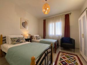 a bedroom with two beds and a chair and a window at Mountain View luxe chalet Ras elhikma families only in Ras Elhekma +66 photos