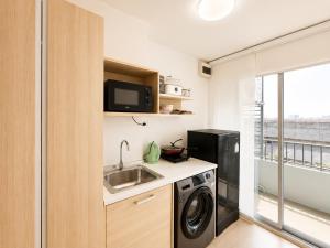 a small kitchen with a sink and a washing machine at Pool Studio Near BTS Quiet Stay in Amphoe Phra Khanong