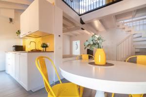 a kitchen and dining room with a white table and yellow chairs at L'appartamento giallo zafferano in Fanano