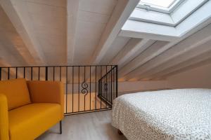 a bedroom with a bed and a yellow chair at L'appartamento giallo zafferano in Fanano