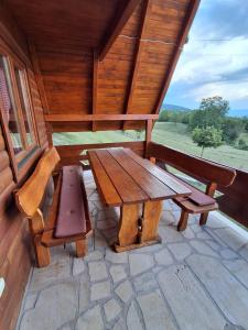 a wooden table and benches on the porch of a cabin at Domaćinstvo braća Rebić in Gacko