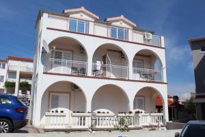 a white building with balconies and a car parked in front at Apartment Joso in Primošten