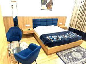 a bedroom with a bed and two blue chairs at K D Motels in Patiāla