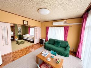a living room with a green couch and a bed at Horomisou in Noboribetsu