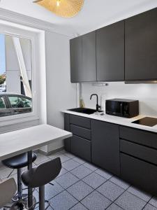 a kitchen with black cabinets and a table and chairs at Casa Dax - Centre - Moderne - Linge inclus in Dax +20 photos