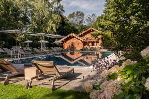 a swimming pool with chairs and a house at Resort Das Achental in Grassau