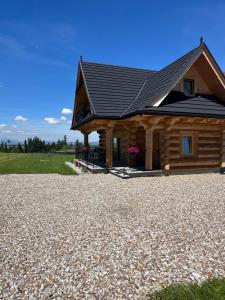 a log cabin with a black roof on a gravel driveway at Osada Groń in Groń