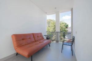 an orange leather couch sitting on a balcony at RedDoorz Plus at Kencana Residence Jimbaran in Jimbaran