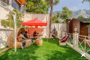 a group of people sitting in a backyard with a tent at Zostel Homes Mussoorie, Mall Road in Mussoorie +30 photos