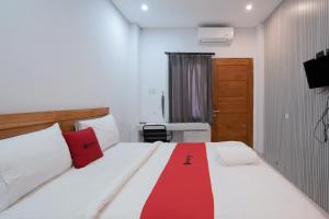 a bedroom with a bed with a red blanket on it at RedDoorz Plus at Kencana Residence Jimbaran in Jimbaran