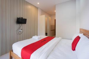 a bedroom with two beds and a tv on the wall at RedDoorz Plus at Kencana Residence Jimbaran in Jimbaran