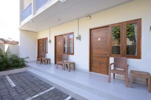 a corridor of a building with wooden doors and chairs at RedDoorz Plus at Kencana Residence Jimbaran in Jimbaran