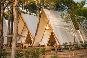 a tent with tables and chairs in a forest at Kampaoh Costa Brava in Pals