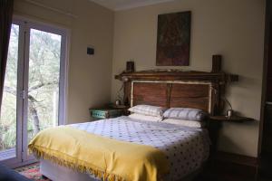 a bedroom with a bed with a wooden headboard and a window at Hangman's Lookout in Calitzdorp