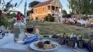 a table with plates of food and a bottle of wine at Joe Bácsi Rezidenciája in Kisharsány