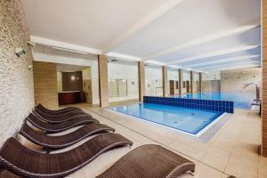 ein großes Schwimmbecken mit einer Reihe von Stühlen drumherum in der Unterkunft Instytut Zdrowia Sofra FIT & SPA in Karpacz