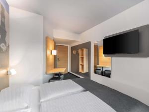 a hotel room with a bed and a flat screen tv at B&B HOTEL St-Pölten in Sankt Pölten