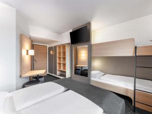 a hotel room with two beds and a desk at B&B HOTEL St-Pölten in Sankt Pölten