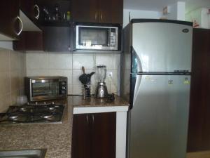 a kitchen with a refrigerator and a microwave at Acogedor departamento con playa privada in Salinas