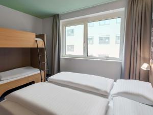 a bedroom with two bunk beds and a window at B&B HOTEL Klagenfurt-City in Klagenfurt