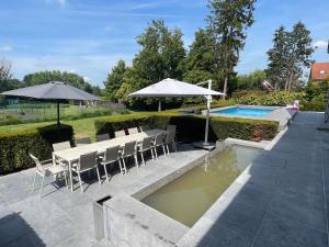 a patio with a table and umbrella and a pool at Exclusive Villa Gentbos - max 28 beds and 6bathrooms, wellness, pool, tennis, fitness, party room in Pataterhoek