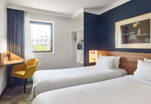 a hotel room with two beds and a chair at B&B HOTEL Paris 17 Batignolles in Paris +36 photos