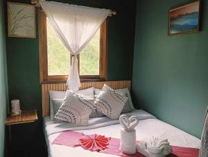 a bed with a window and some towels on it at เวนิสบ้านเวร in Ban Khun Nam Nan