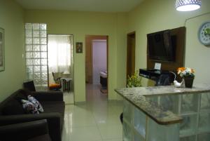 uma sala de estar com um sofá e uma cozinha com um balcão em Apartment Djalma Ulrich no Rio de Janeiro