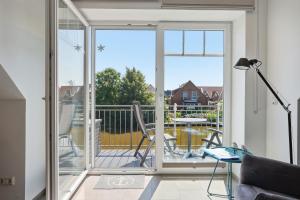 a living room with a sliding glass door leading to a balcony at Grachtenrefugium in Greetsiel