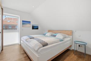 a white bedroom with a bed and a window at Grachtenrefugium in Greetsiel