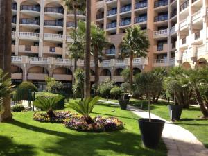 a park in front of a building with palm trees and flowers at Résidence La Palme d’Azur – Cannes in Cannes