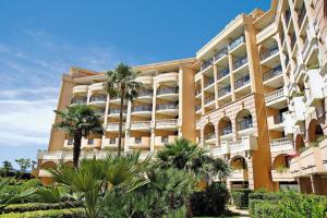 a large building with palm trees in front of it at Résidence La Palme d’Azur – Cannes in Cannes