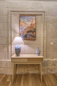a table with a lamp and a painting on a wall at Dar Vitorja in Senglea +58 photos