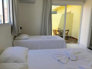 two beds in a room with a view of a patio at Planalto Hotel Arujá in Arujá