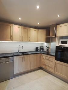 a kitchen with wooden cabinets and black counter tops at Gîte Aux 3 Épis, Classé 3 Étoiles in Dienville