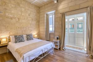 a bedroom with a bed and a large window at Dar Vitorja in Senglea