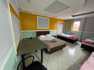 a room with two beds and a table in it at Hotel Vitória de Santos in Santos