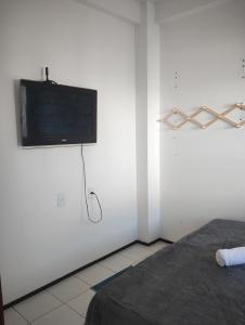 a bedroom with a flat screen tv on a white wall at House Hotel Slz in São Luís